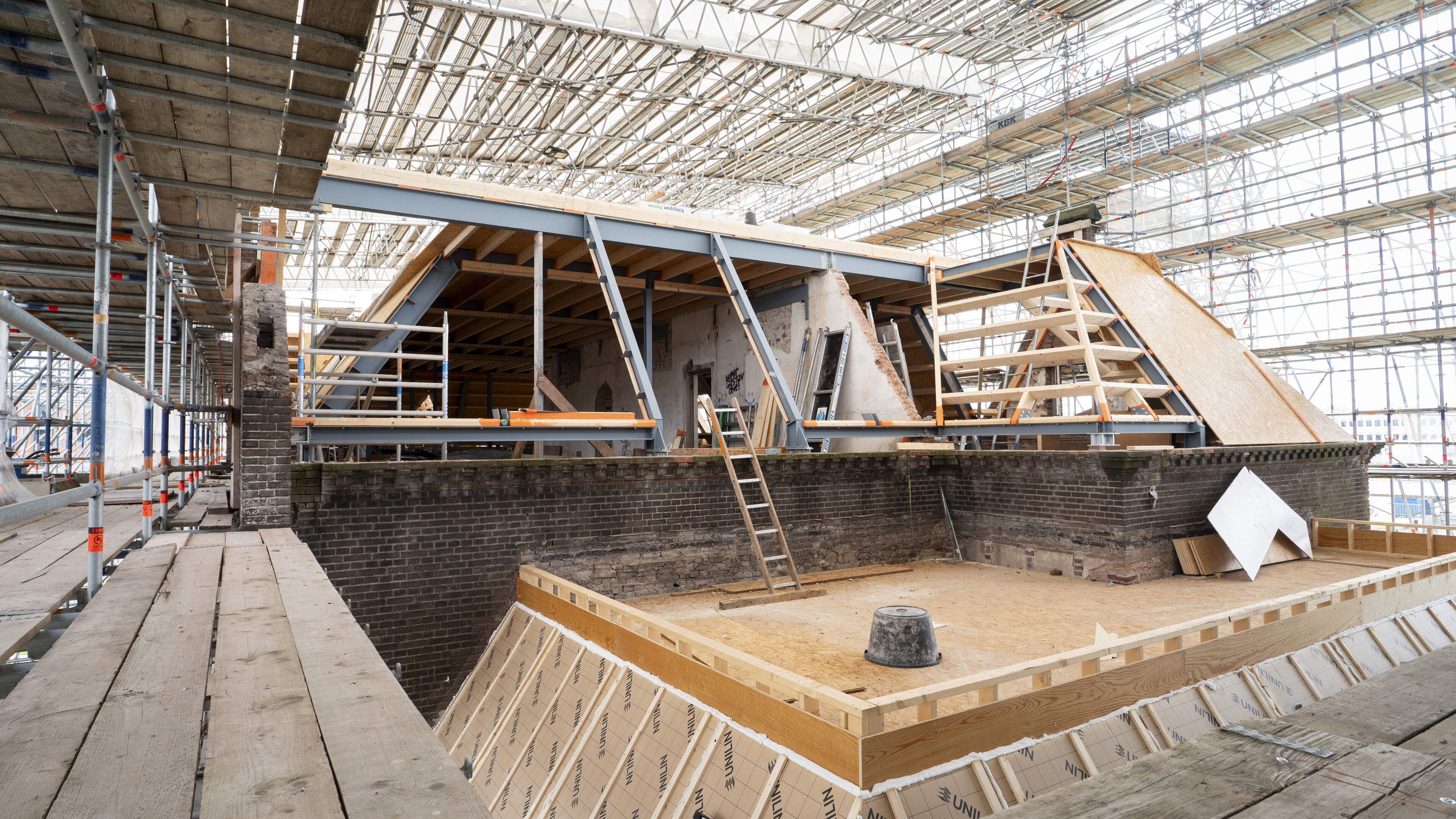 Dwalen tussen de imposante steigers rond een monumentale ruïne. ’Kijk, de ruim honderd jaar oude buurman in Oost krabbelt toch weer op’