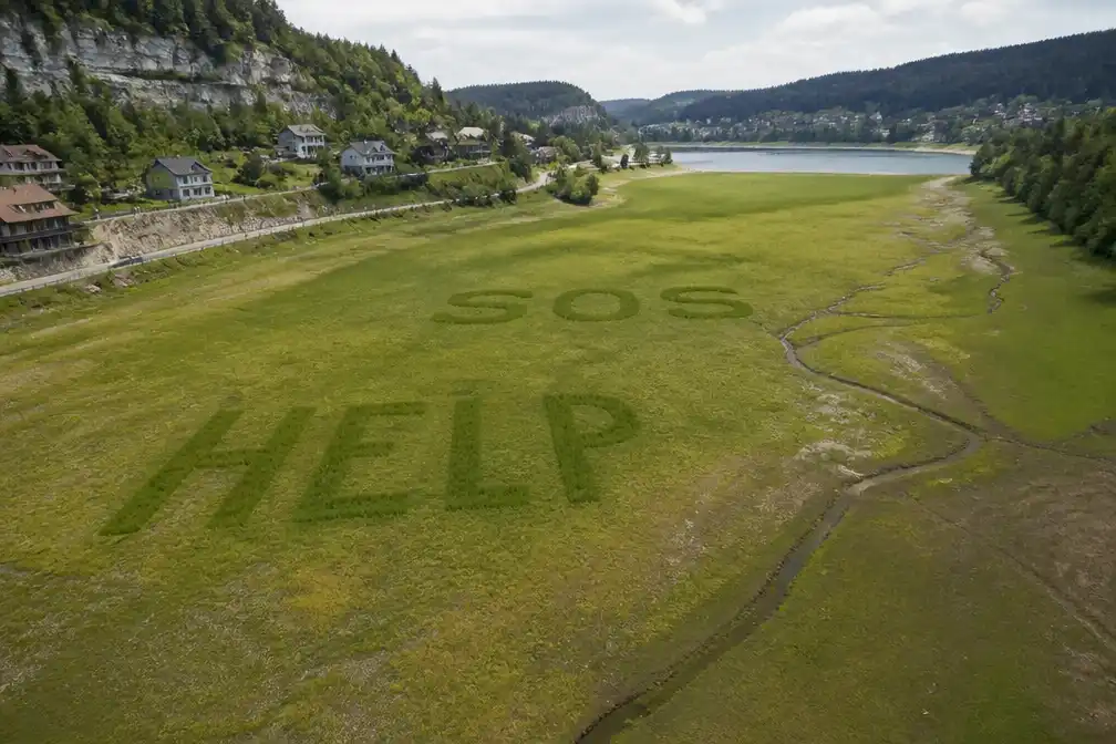 Bewoners schrijven reusachtig HELP op drooggevallen Lac des Brenets uit protest